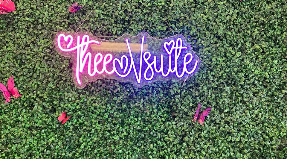 Thee V Suite neon sign and green feature wall inside the studio