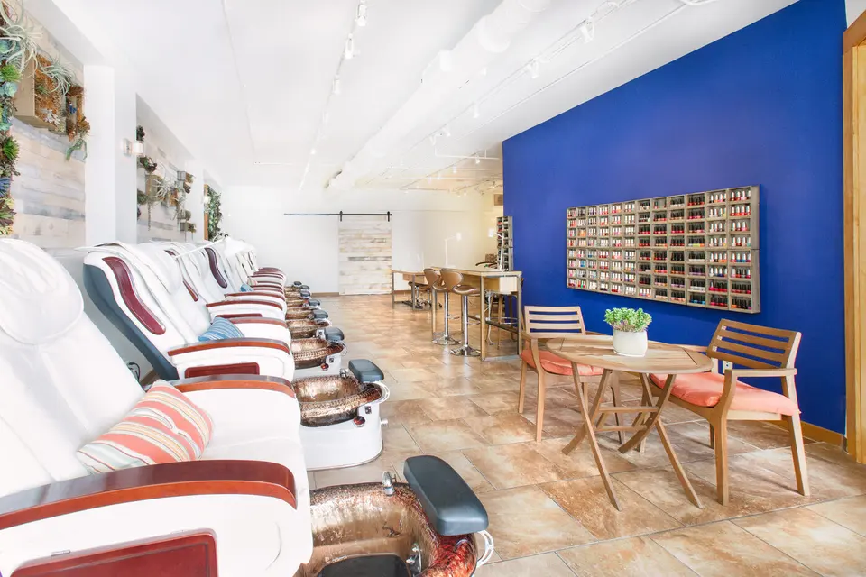 Venice Soleil salon interior with white pedicure chairs, a blue polish-display wall and manicure tables